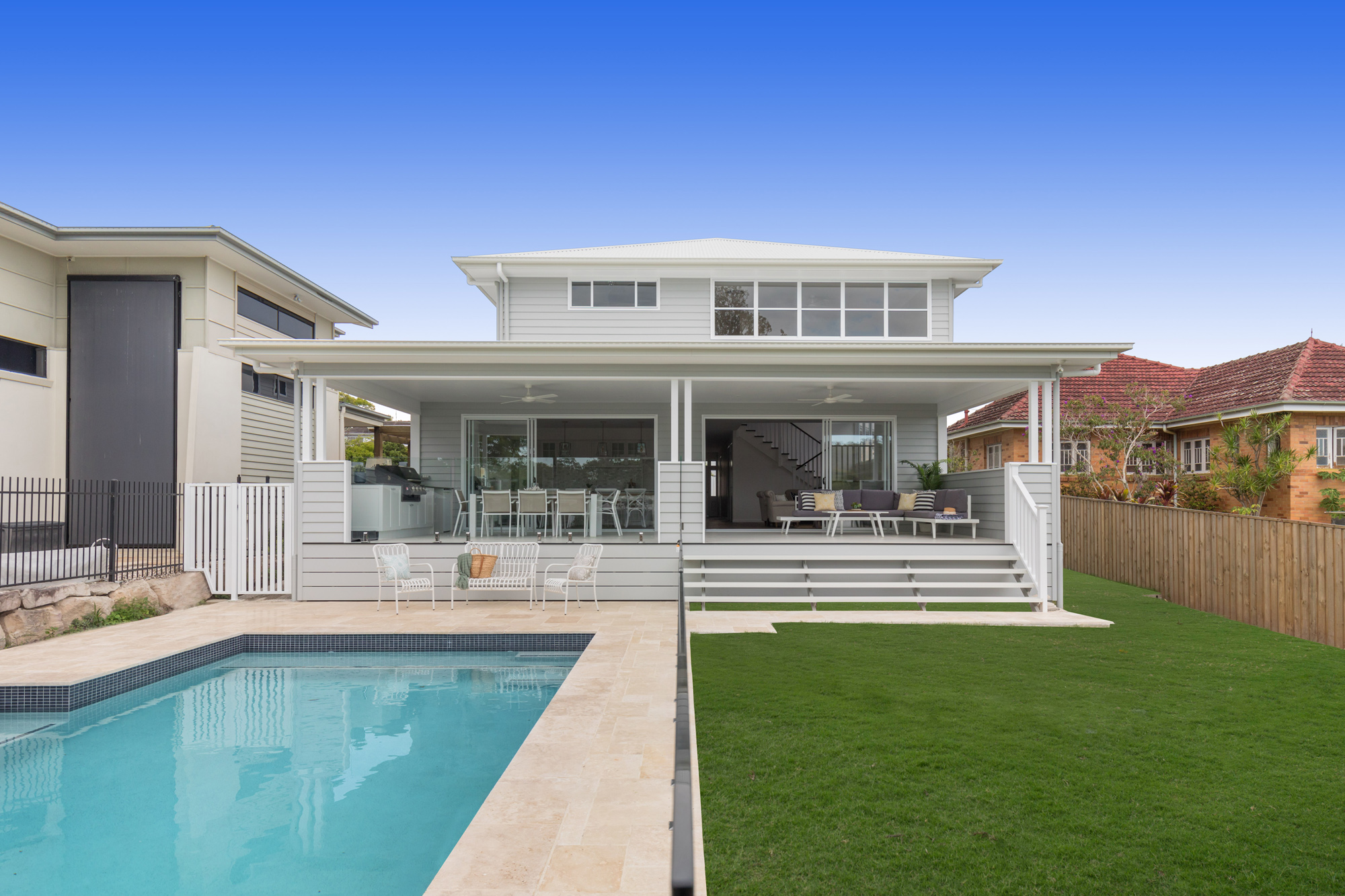 White Hampton and Queenslander style house with a backyard swimming pool